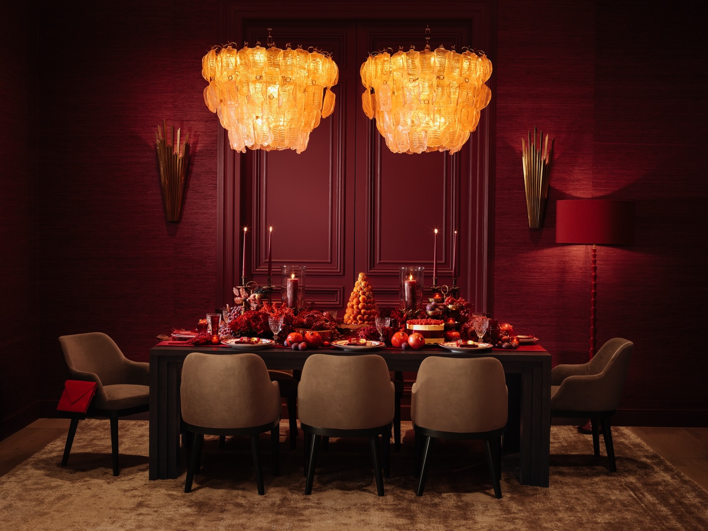 Crimson dining room with twin amber Murano chandeliers above a candlelit holiday table.